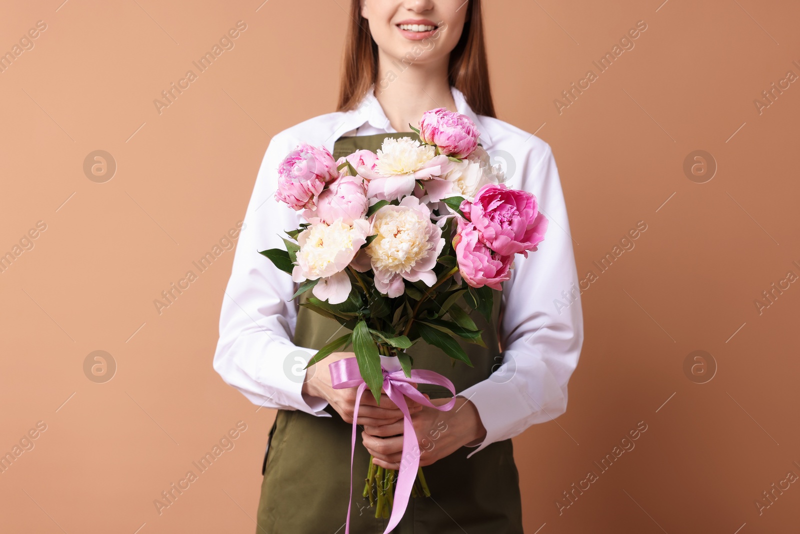 Florist with beautiful bouquet of peonies on dark beige background, closeup Photo of Florist with beautiful bouquet of peonies on dark beige background, closeup