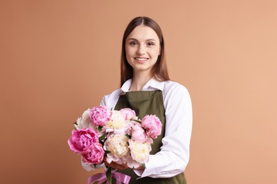 Photo of Florist with beautiful bouquet of peonies on dark beige background