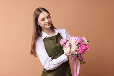 Photo of Florist with beautiful bouquet of peonies on dark beige background