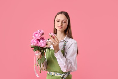 Photo of Florist with beautiful peonies on pink background