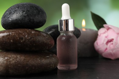 Photo of Spa composition with wet stones and dropper on dark table against blurred green background, closeup
