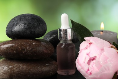 Photo of Spa composition with wet stones, dropper and flower on dark table against blurred green background, closeup
