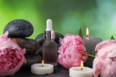 Photo of Spa composition with wet stones, dropper and flowers on dark table against blurred green background, closeup