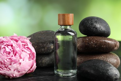 Photo of Spa composition with wet stones, cosmetic product and flower on dark textured table against blurred green background, closeup