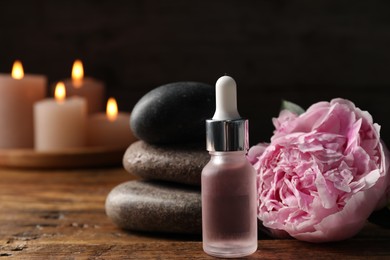 Photo of Spa composition with dropper, stones and flower on wooden table against black background, closeup