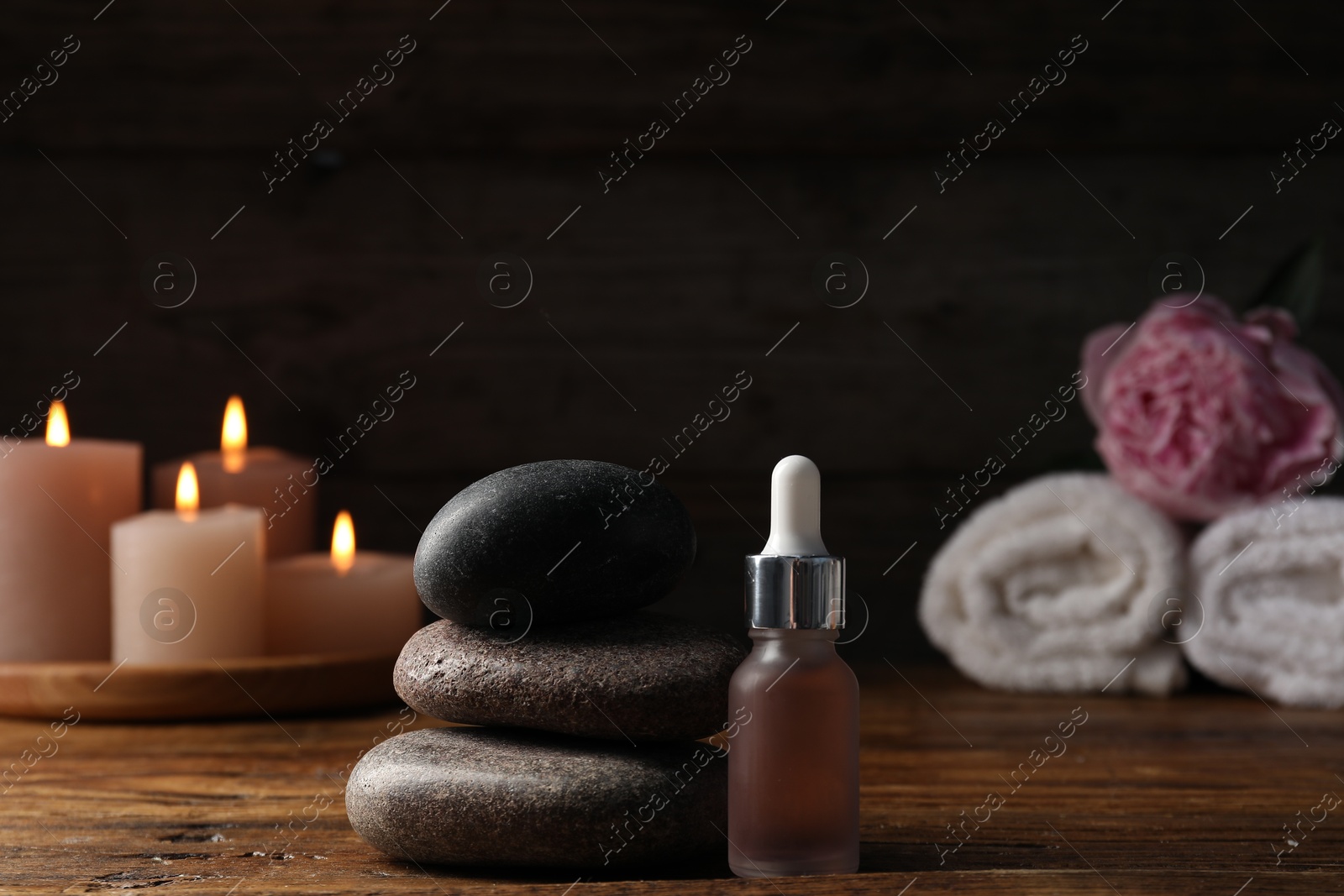 Spa composition with stack of stones and dropper on wooden table against black background, closeup Photo of Spa composition with stack of stones and dropper on wooden table against black background, closeup