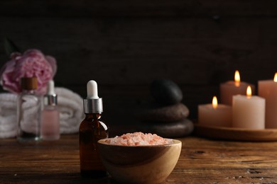 Photo of Spa composition with cosmetic products on wooden table against black background, closeup