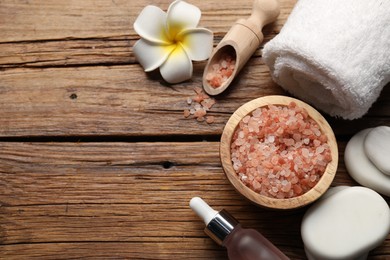 Photo of Flat lay composition with spa stones, cosmetic products and flower on wooden table. Space for text