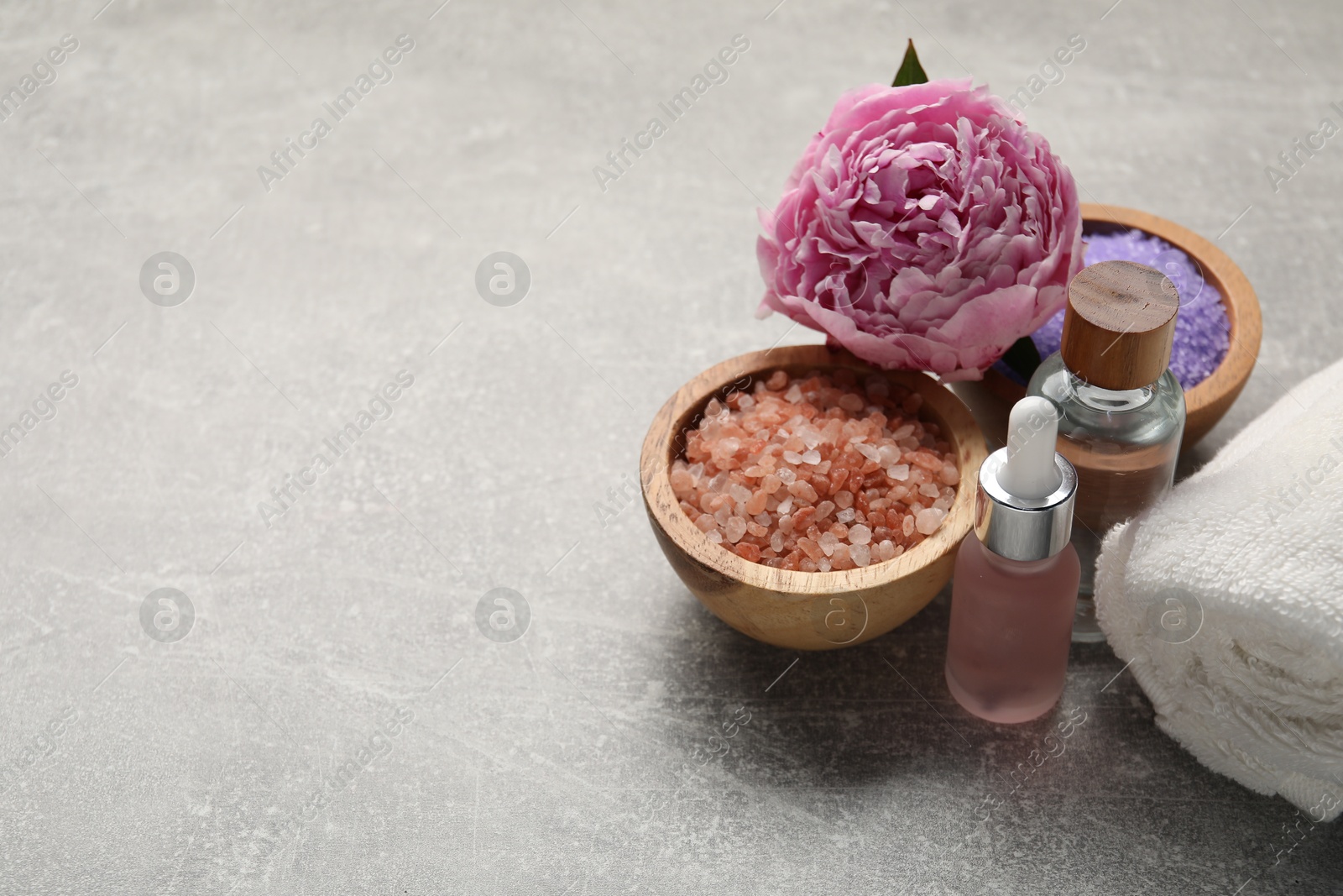 Spa products, flower and towel on grey textured table, closeup. Space for text Photo of Spa products, flower and towel on grey textured table, closeup. Space for text