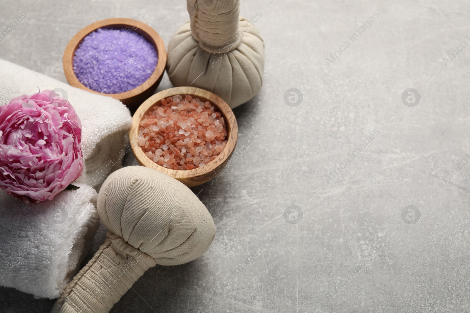 Spa composition with herbal bags, sea salt and towels on grey textured table, above view. Space for text Photo of Spa composition with herbal bags, sea salt and towels on grey textured table, above view. Space for text