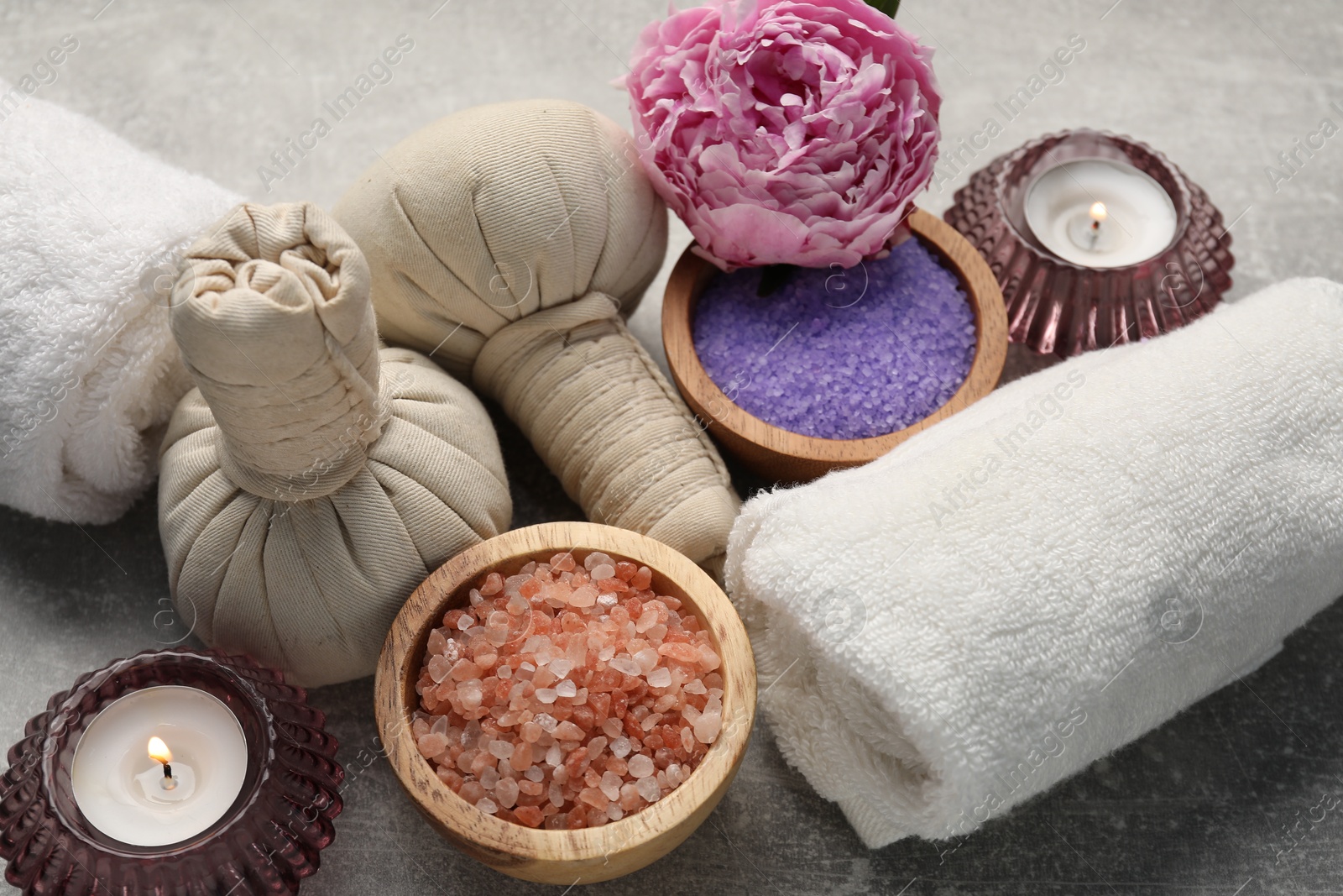 Spa composition with herbal bags, sea salt and towels on grey textured table, closeup Photo of Spa composition with herbal bags, sea salt and towels on grey textured table, closeup