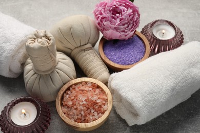 Photo of Spa composition with herbal bags, sea salt and towels on grey textured table, closeup