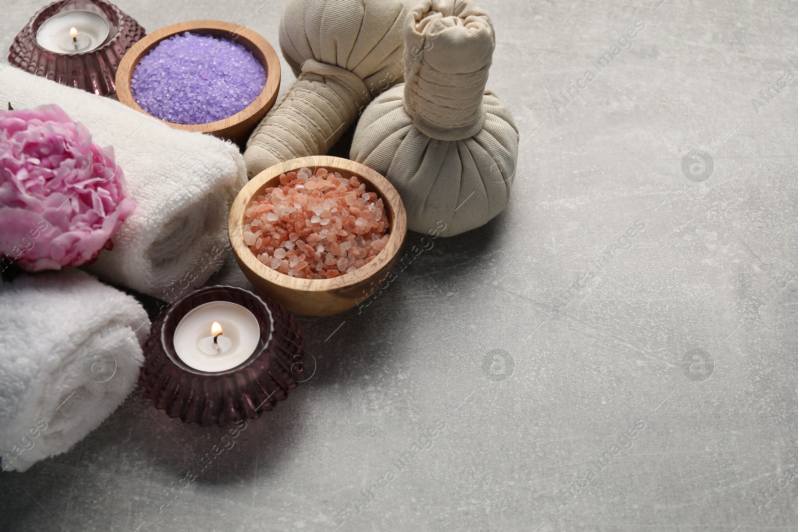 Spa composition with herbal bags, sea salt and towels on grey textured table. Space for text Photo of Spa composition with herbal bags, sea salt and towels on grey textured table. Space for text