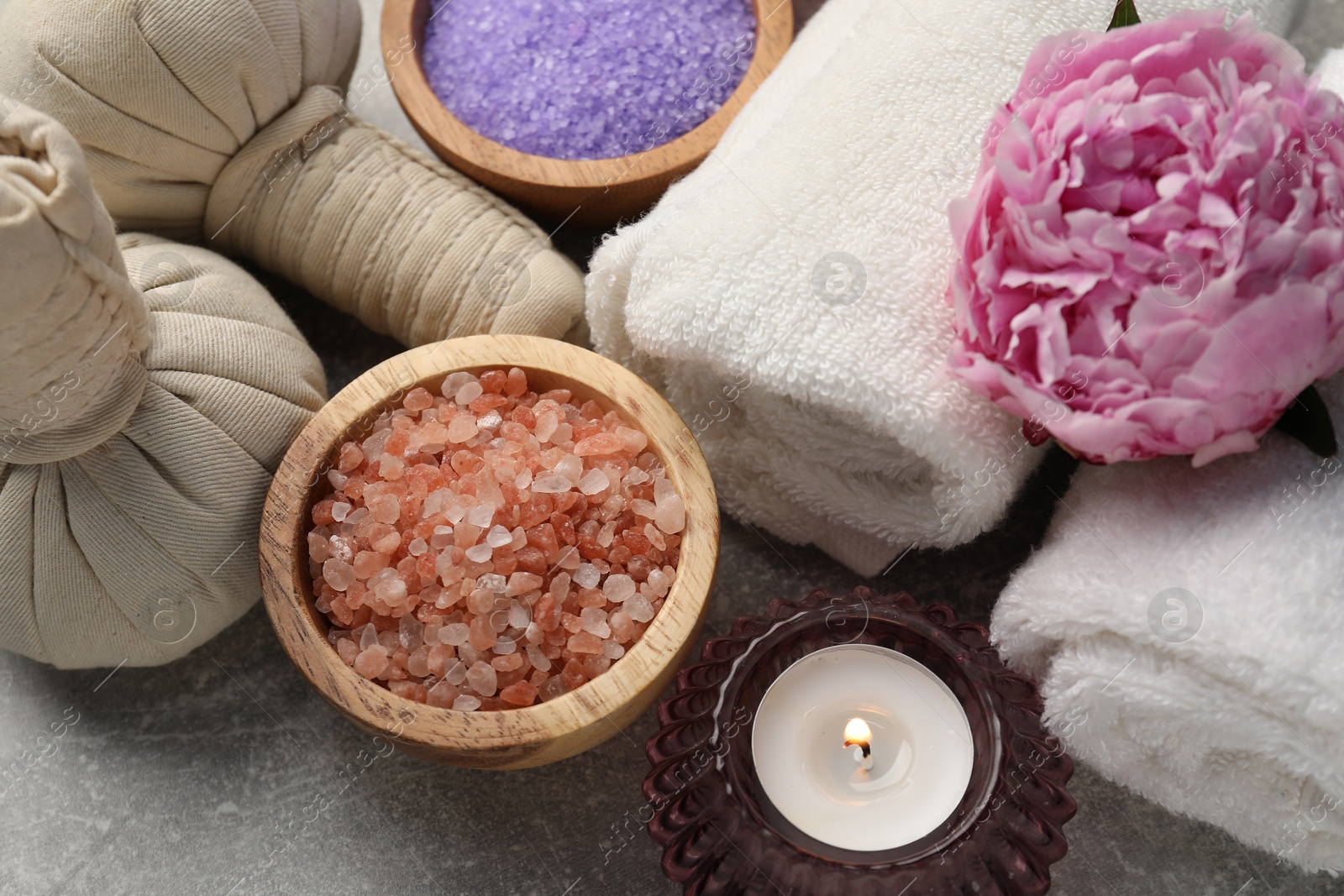 Spa composition with herbal bags, sea salt and towels on grey textured table, above view Photo of Spa composition with herbal bags, sea salt and towels on grey textured table, above view
