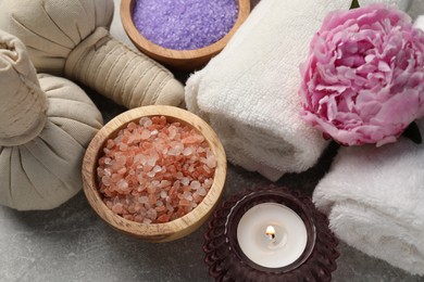 Photo of Spa composition with herbal bags, sea salt and towels on grey textured table, above view