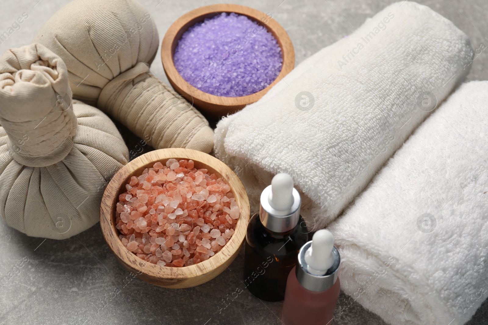 Spa composition with herbal bags, cosmetic products and towels on grey textured table Photo of Spa composition with herbal bags, cosmetic products and towels on grey textured table