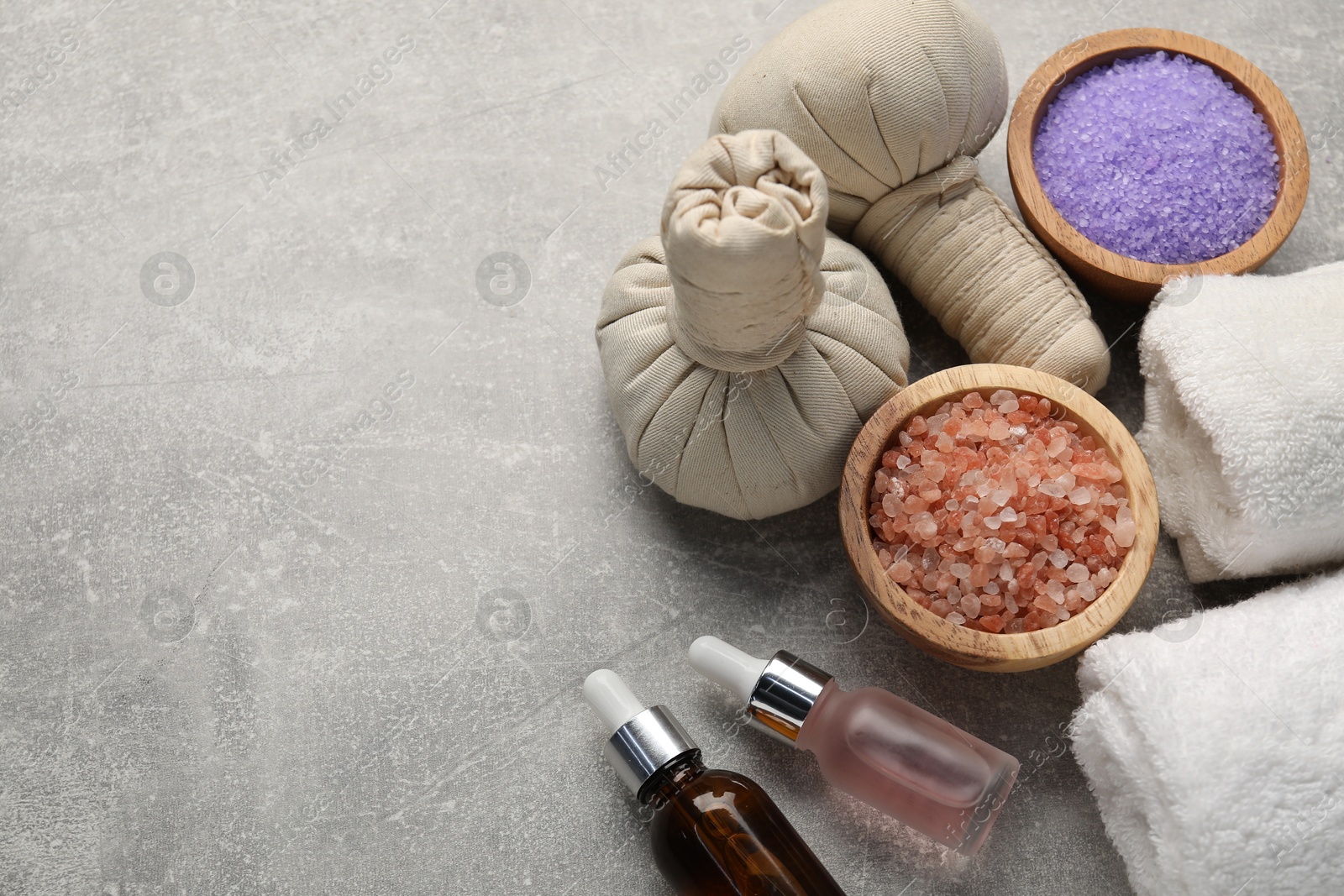 Spa composition with herbal bags, cosmetic products and towels on grey textured table, above view. Space for text Photo of Spa composition with herbal bags, cosmetic products and towels on grey textured table, above view. Space for text