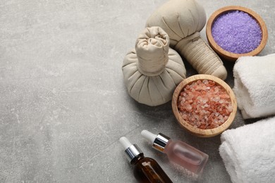 Photo of Spa composition with herbal bags, cosmetic products and towels on grey textured table, above view. Space for text