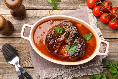 Photo of Traditional ossobuco dish with beef steak served on wooden table, flat lay