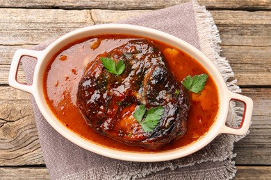 Photo of Traditional ossobuco dish with beef steak and sauce on wooden table, top view