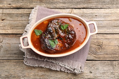 Photo of Traditional ossobuco dish with beef steak and sauce on wooden table, top view