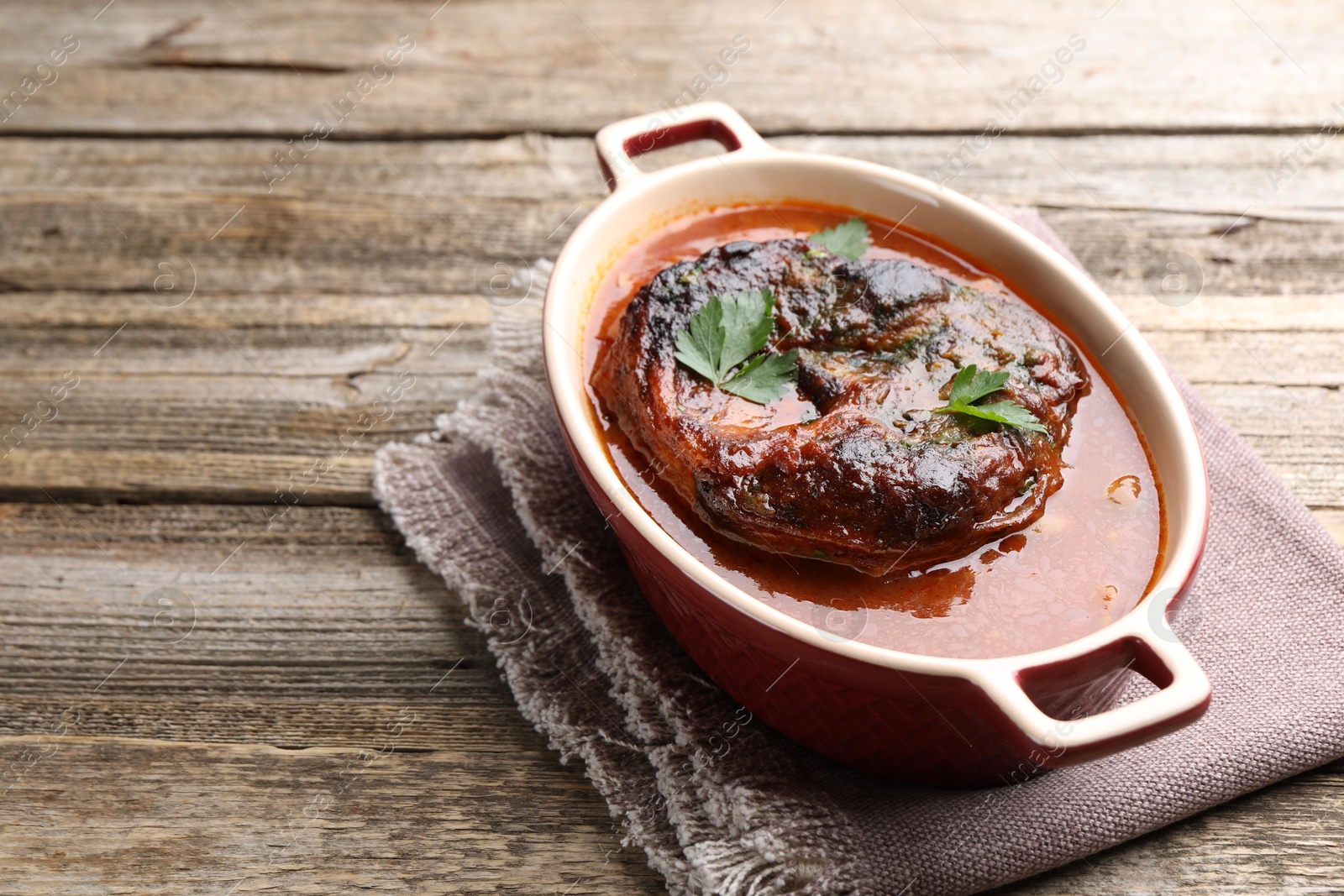 Traditional ossobuco dish with beef steak and sauce on wooden table, closeup Photo of Traditional ossobuco dish with beef steak and sauce on wooden table, closeup