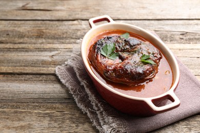 Photo of Traditional ossobuco dish with beef steak and sauce on wooden table, closeup