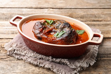 Photo of Traditional ossobuco dish with beef steak and sauce on wooden table, closeup