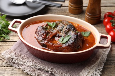 Photo of Traditional ossobuco dish with beef steak and sauce served on wooden table, closeup
