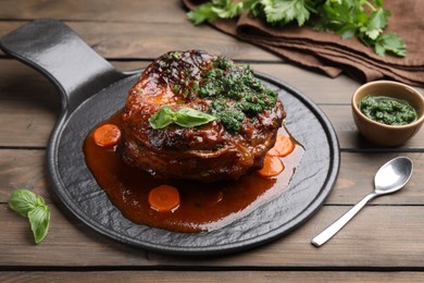 Photo of Traditional ossobuco dish with beef steak and sauce served on wooden table, closeup