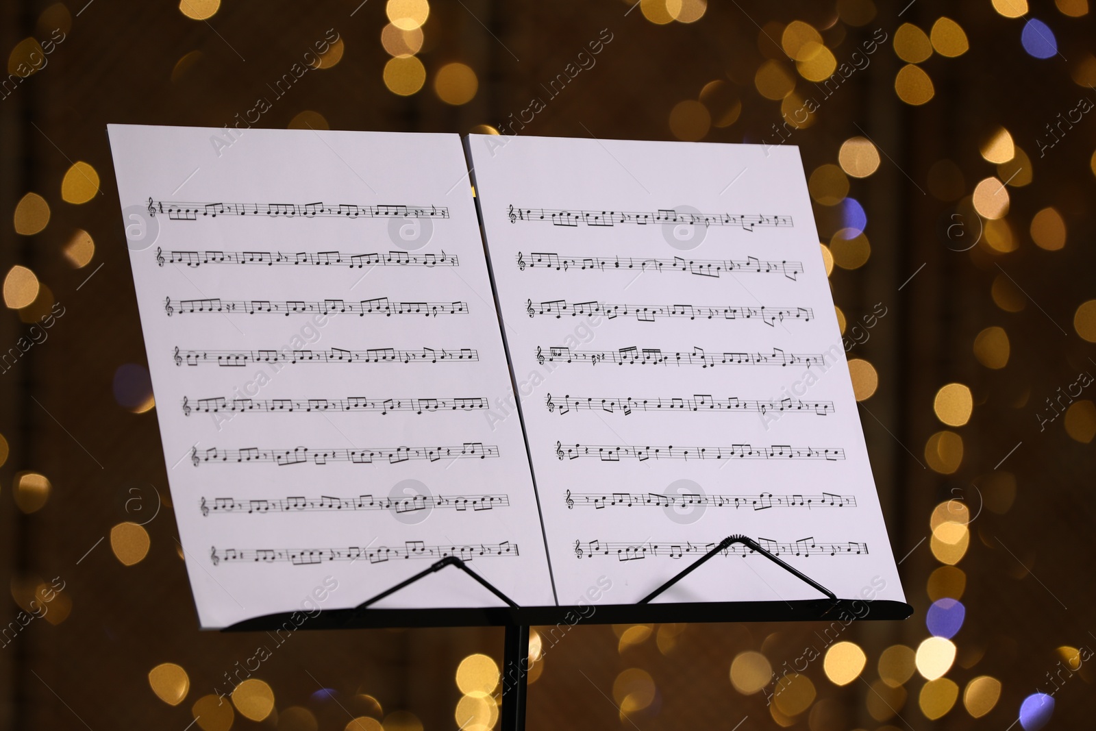 Note stand with music sheets against blurred lights, closeup. Bokeh effect Photo of Note stand with music sheets against blurred lights, closeup. Bokeh effect