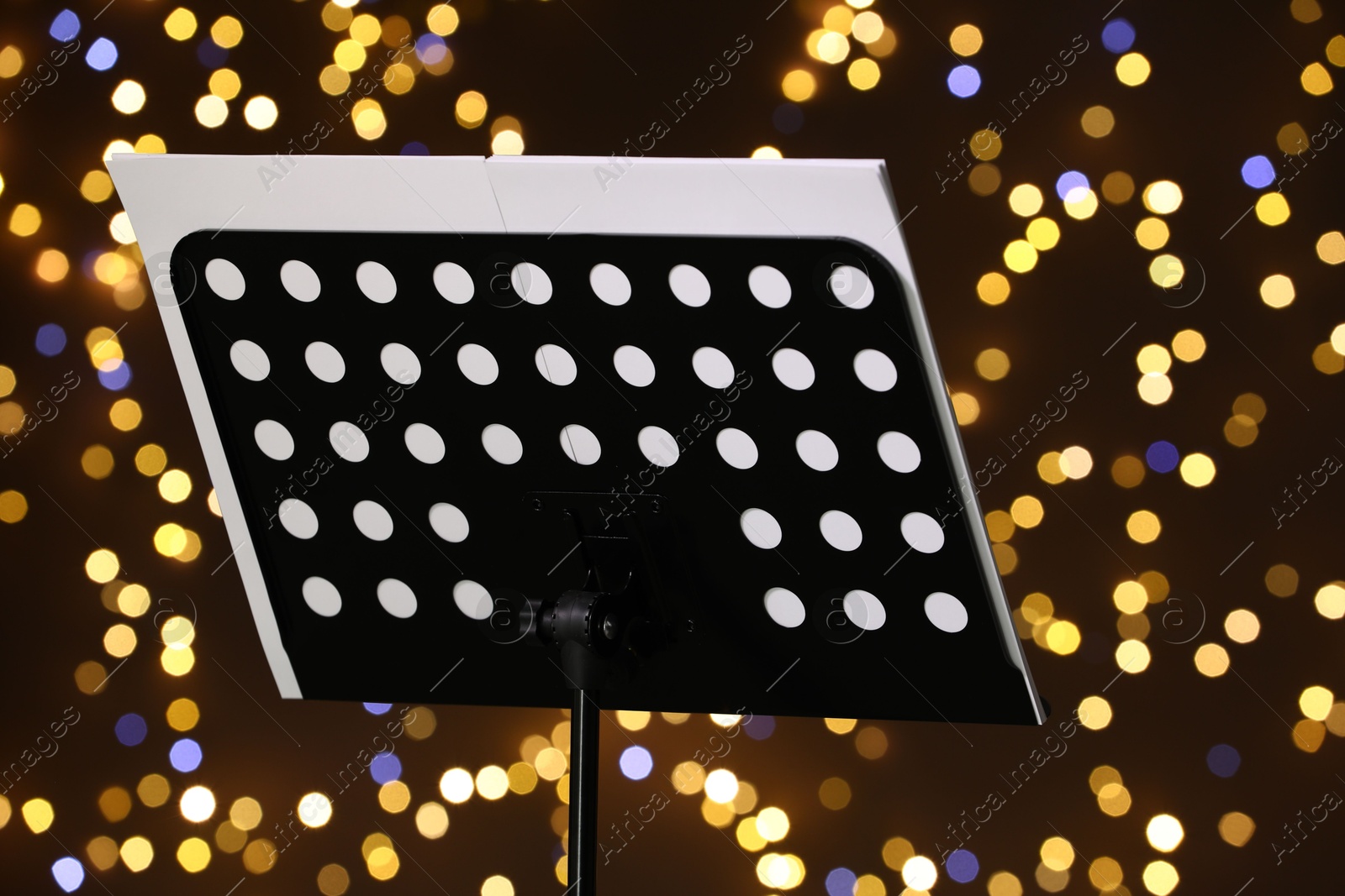 Note stand with music sheets against blurred lights, closeup. Bokeh effect Photo of Note stand with music sheets against blurred lights, closeup. Bokeh effect