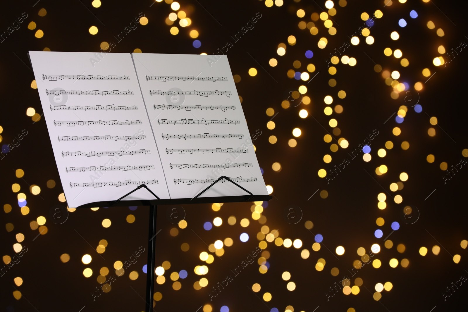 Note stand with music sheets against blurred lights, closeup. Space for text Photo of Note stand with music sheets against blurred lights, closeup. Space for text