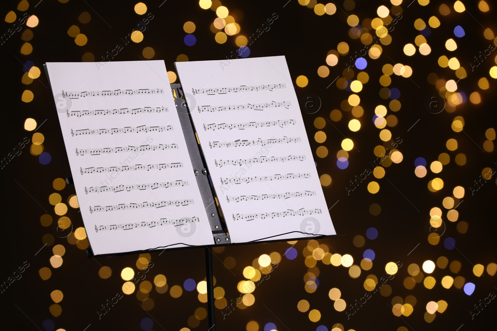 Note stand with music sheets against blurred lights, closeup. Bokeh effect Photo of Note stand with music sheets against blurred lights, closeup. Bokeh effect