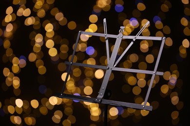 Photo of One empty note stand against blurred lights, closeup. Bokeh effect