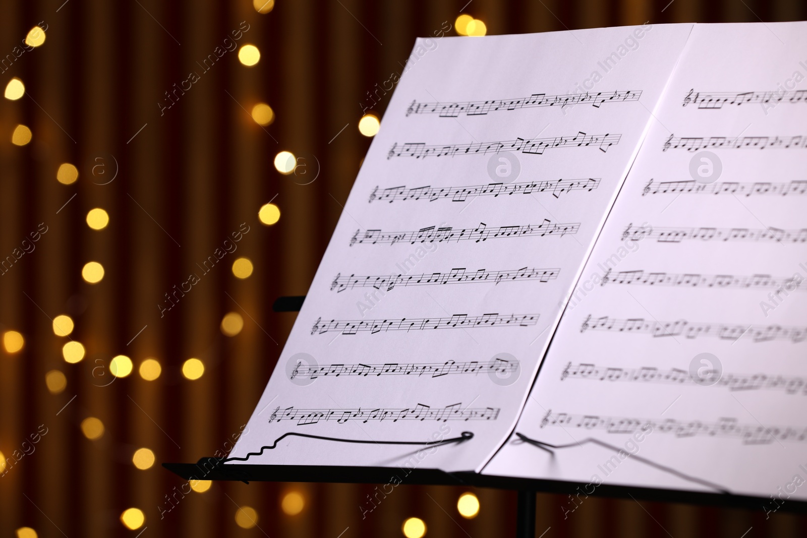 Note stand with music sheets against blurred lights, closeup. Space for text Photo of Note stand with music sheets against blurred lights, closeup. Space for text