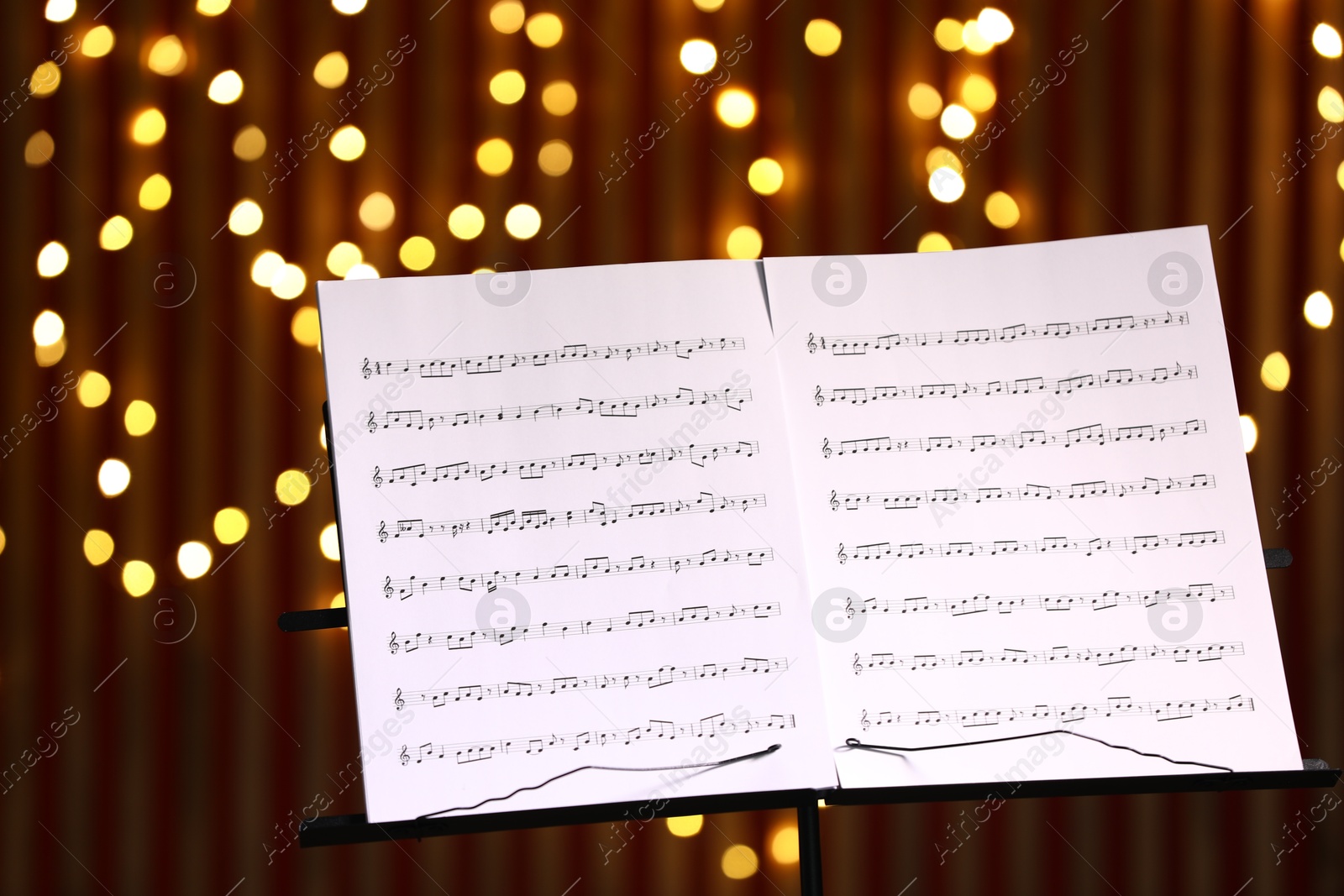 Note stand with music sheets against blurred lights, closeup. Bokeh effect Photo of Note stand with music sheets against blurred lights, closeup. Bokeh effect