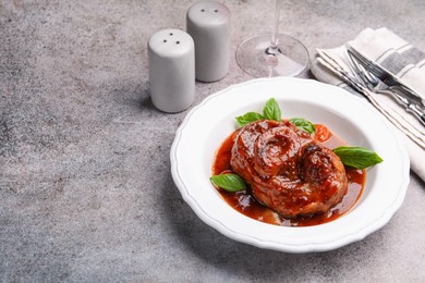 Photo of Traditional ossobuco dish with beef steak served on grey table, above view. Space for text