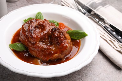Photo of Traditional ossobuco dish with beef steak served on grey table, closeup