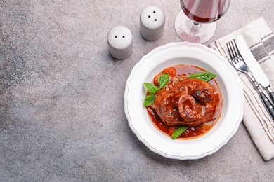 Photo of Traditional ossobuco dish with beef steak served on grey table, flat lay. Space for text
