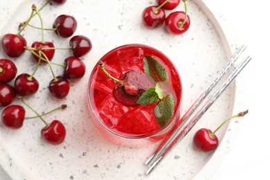 Photo of Tasty cherry soda with ice cubes, mint and berries on white wooden table, flat lay