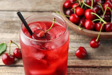 Photo of Tasty cherry soda with ice cubes and berries on wooden table, closeup