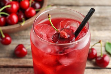 Photo of Tasty cherry soda with ice cubes and berries on wooden table, closeup