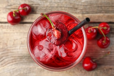 Photo of Tasty cherry soda with ice cubes and berries on wooden table, flat lay