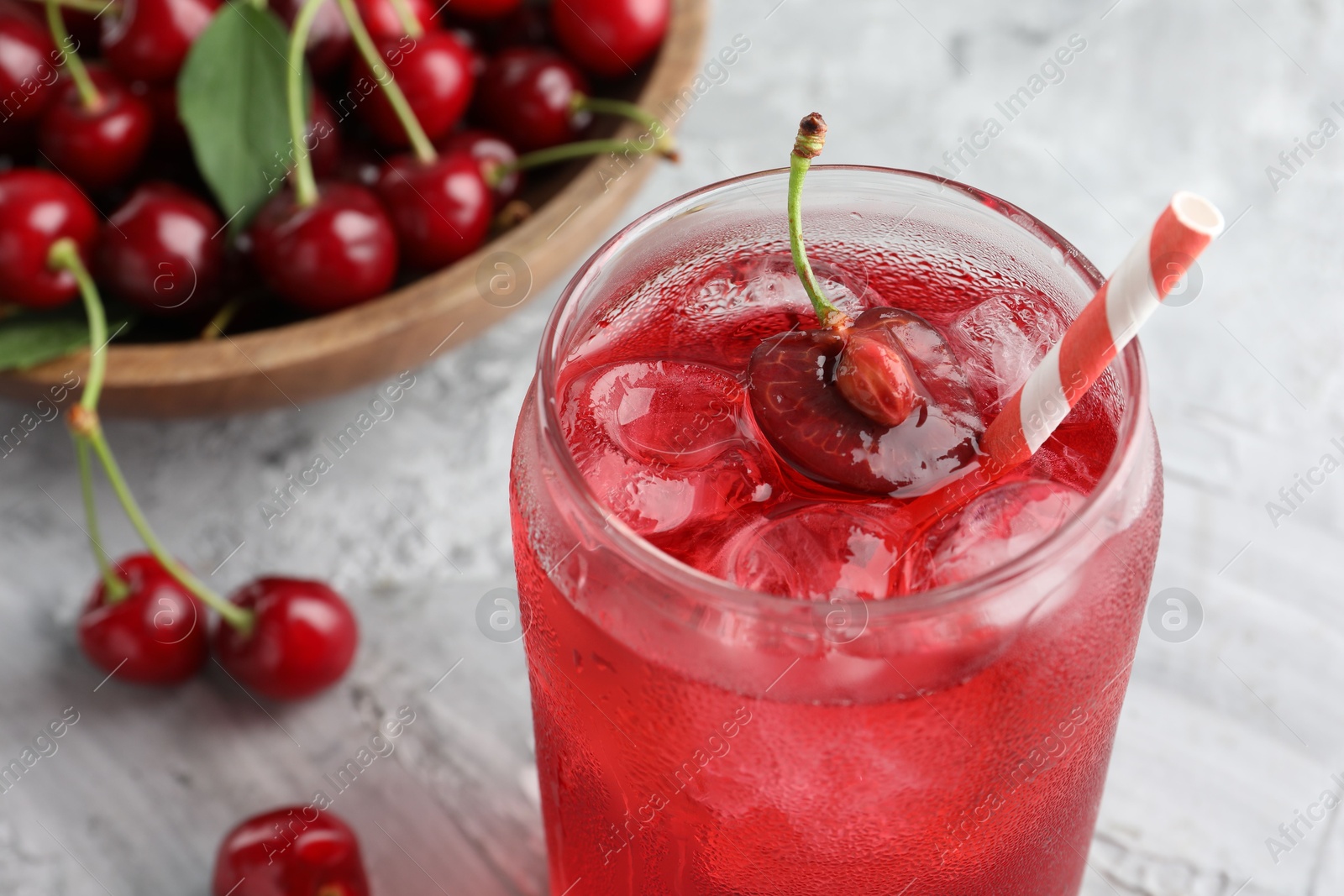 Tasty cherry soda with ice cubes and berries on grey textured table, closeup Photo of Tasty cherry soda with ice cubes and berries on grey textured table, closeup