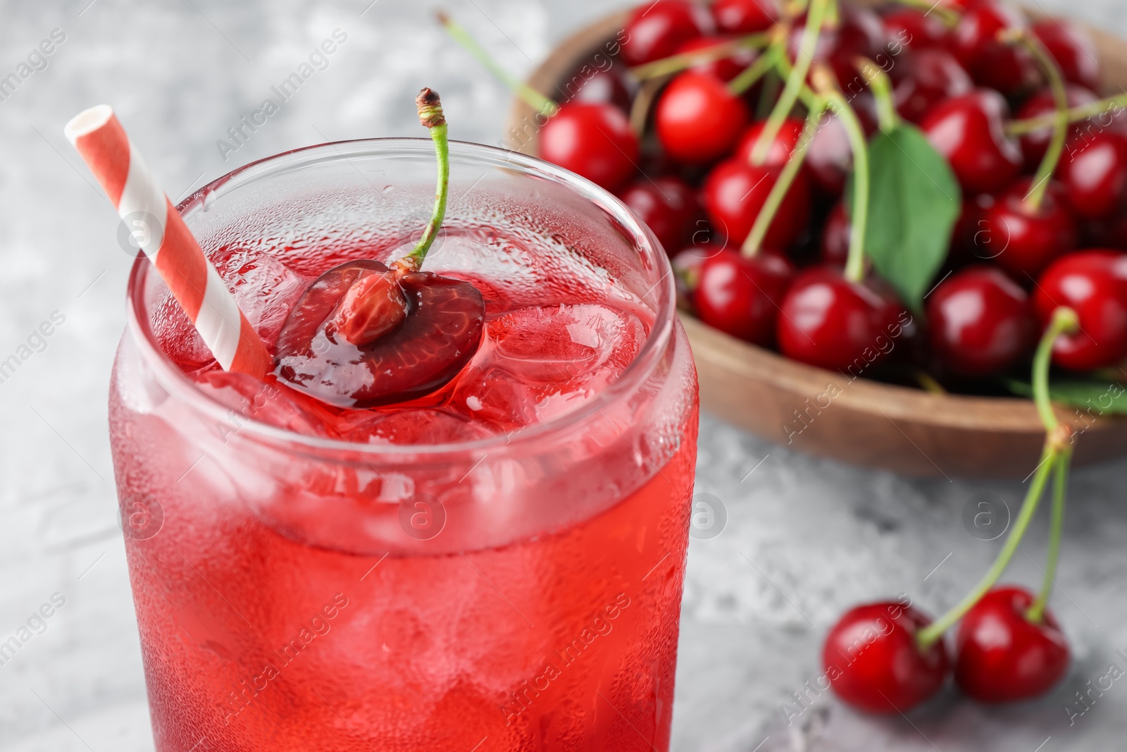 Tasty cherry soda with ice cubes and berries on grey textured table, closeup Photo of Tasty cherry soda with ice cubes and berries on grey textured table, closeup