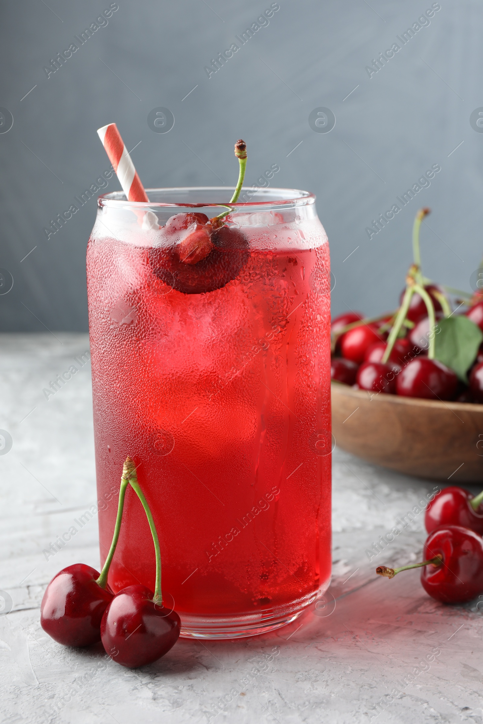 Tasty cherry soda with ice cubes and berries on grey textured table, closeup Photo of Tasty cherry soda with ice cubes and berries on grey textured table, closeup