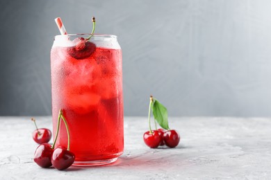 Photo of Tasty cherry soda with ice cubes and berries on grey textured table, closeup. Space for text