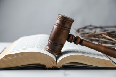 Photo of Judge's gavel, Bible and crown of thorns on white marble table, closeup