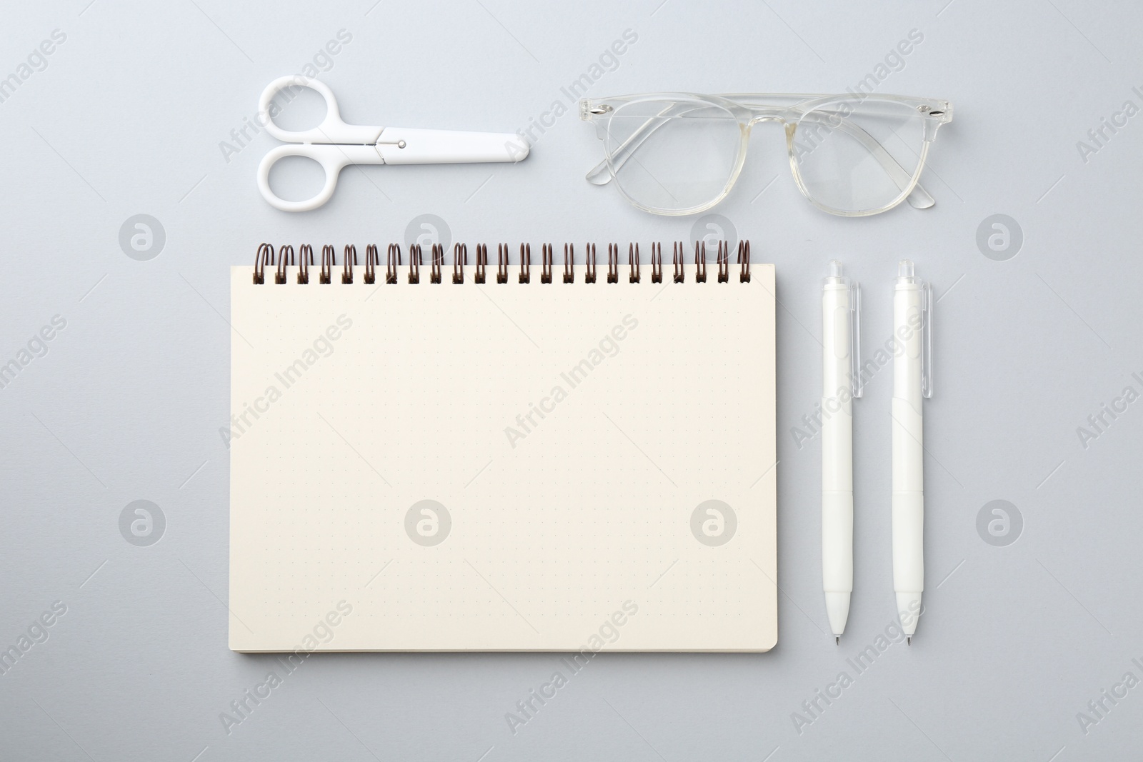 Photo of Notebook, scissors, pens and glasses on gray background, flat lay